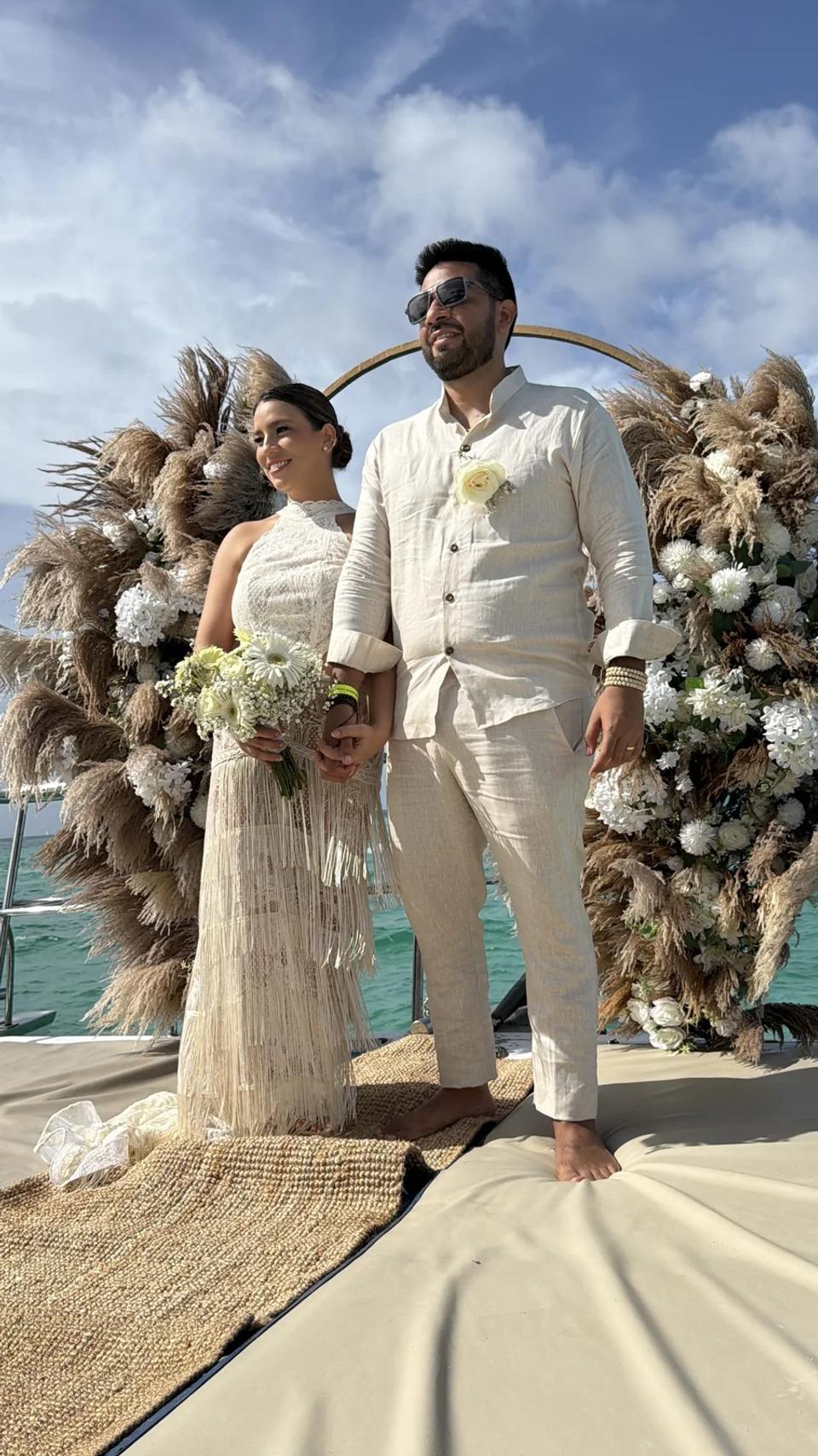 Couple d’elopement sous une arche de pampas sur un catamaran privé à Punta Cana