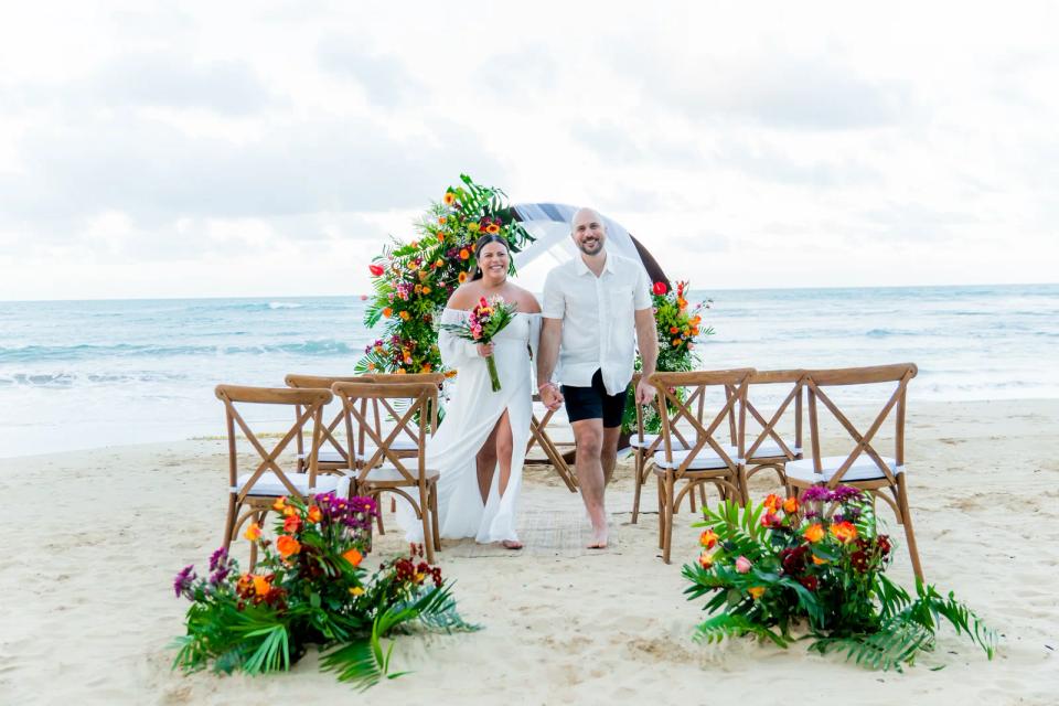Jeunes mariés traversant une cérémonie d’elopement tropicale et colorée sur la plage
