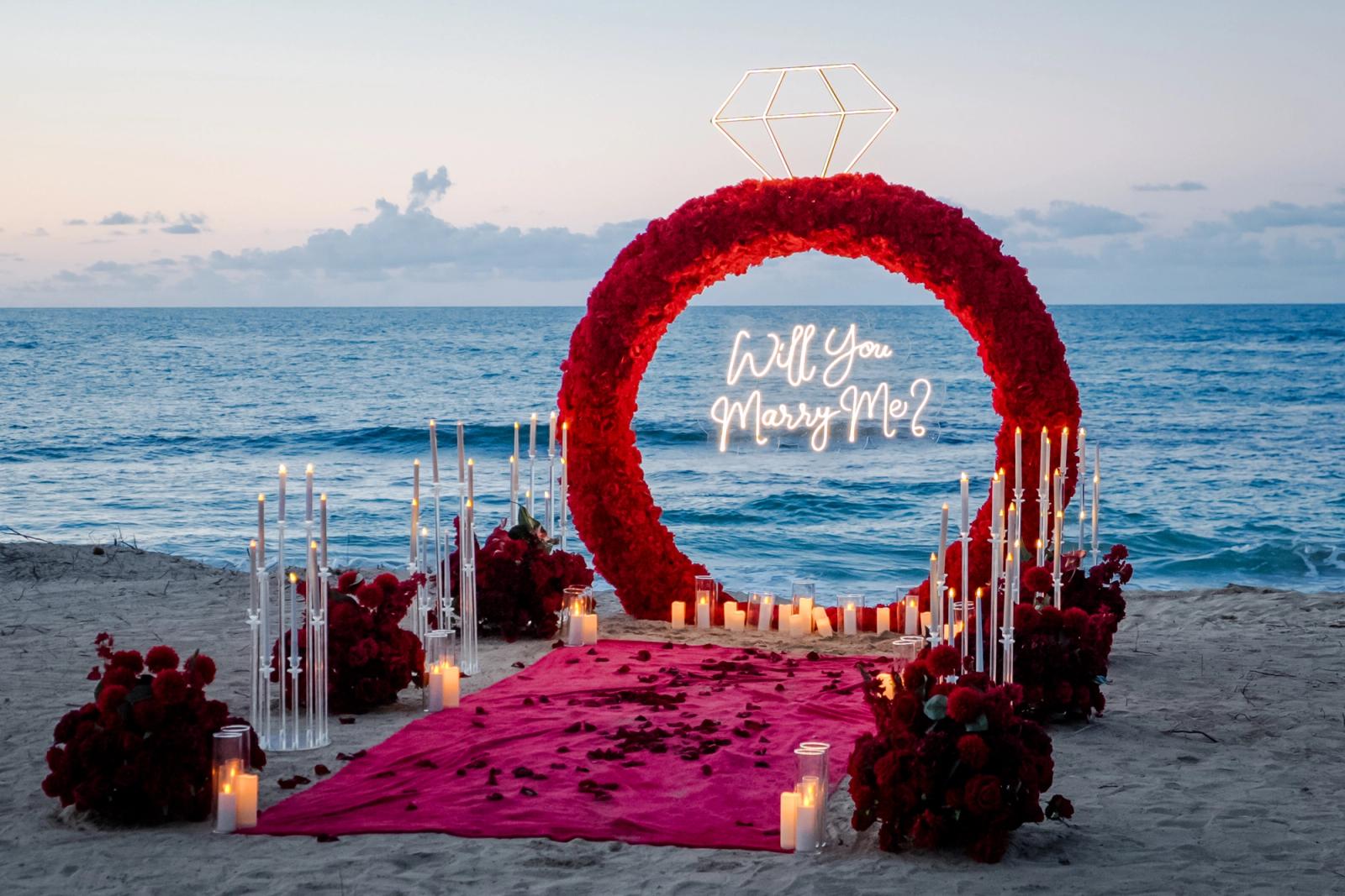 Endless Love: Red floral ring with a glowing diamond and candlelit aisle beside the sea. Endless Love: Red floral ring with a glowing diamond and candlelit aisle beside the sea.