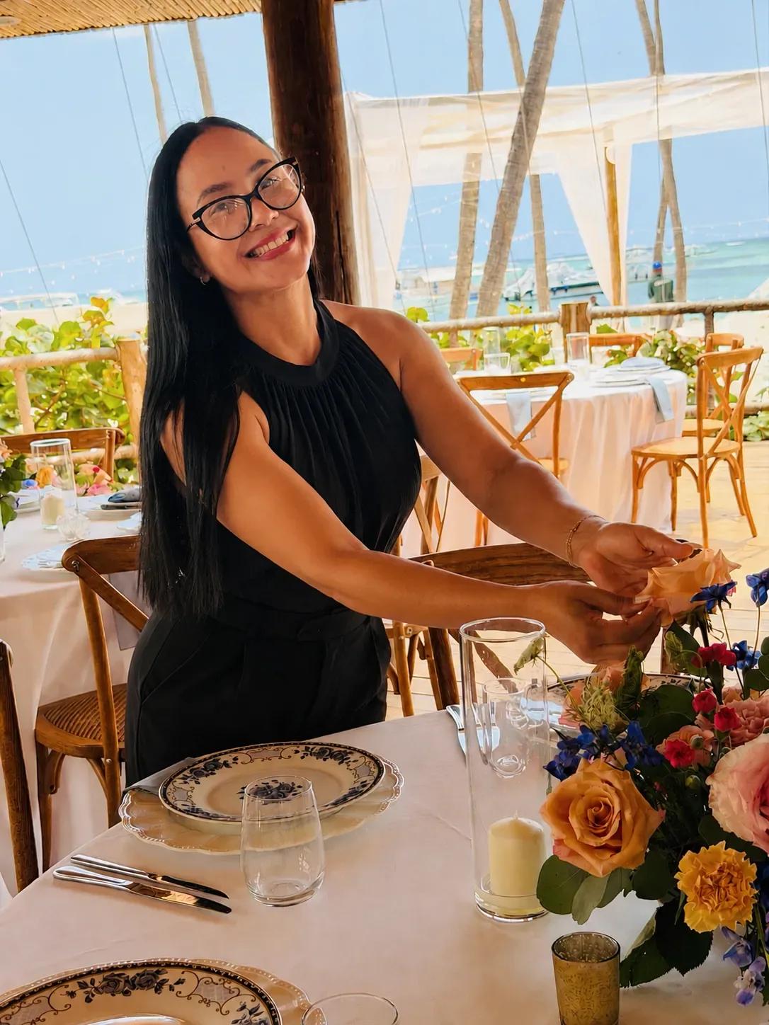 Grecia Mejía preparando uma mesa de recepção sob uma estrutura coberta