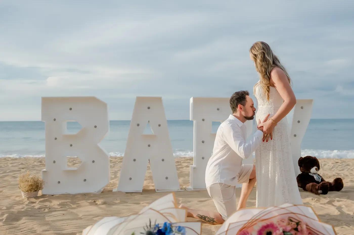 Futurs parents près des lettres Baby lumineuses sur la plage
