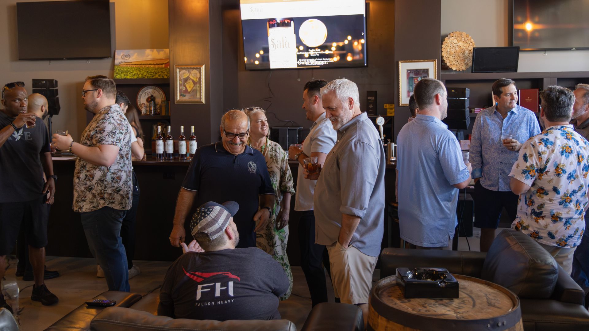Guests socializing at an Orlando Whiskey Alliance tasting event, sipping Safai whiskey around a whiskey barrel table in a cigar lounge