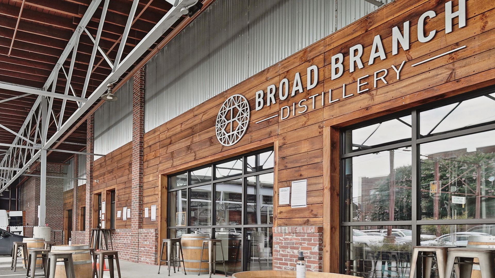 Broad Branch Distillery outdoor patio with barrel tables and metal stools along the wood-paneled storefront