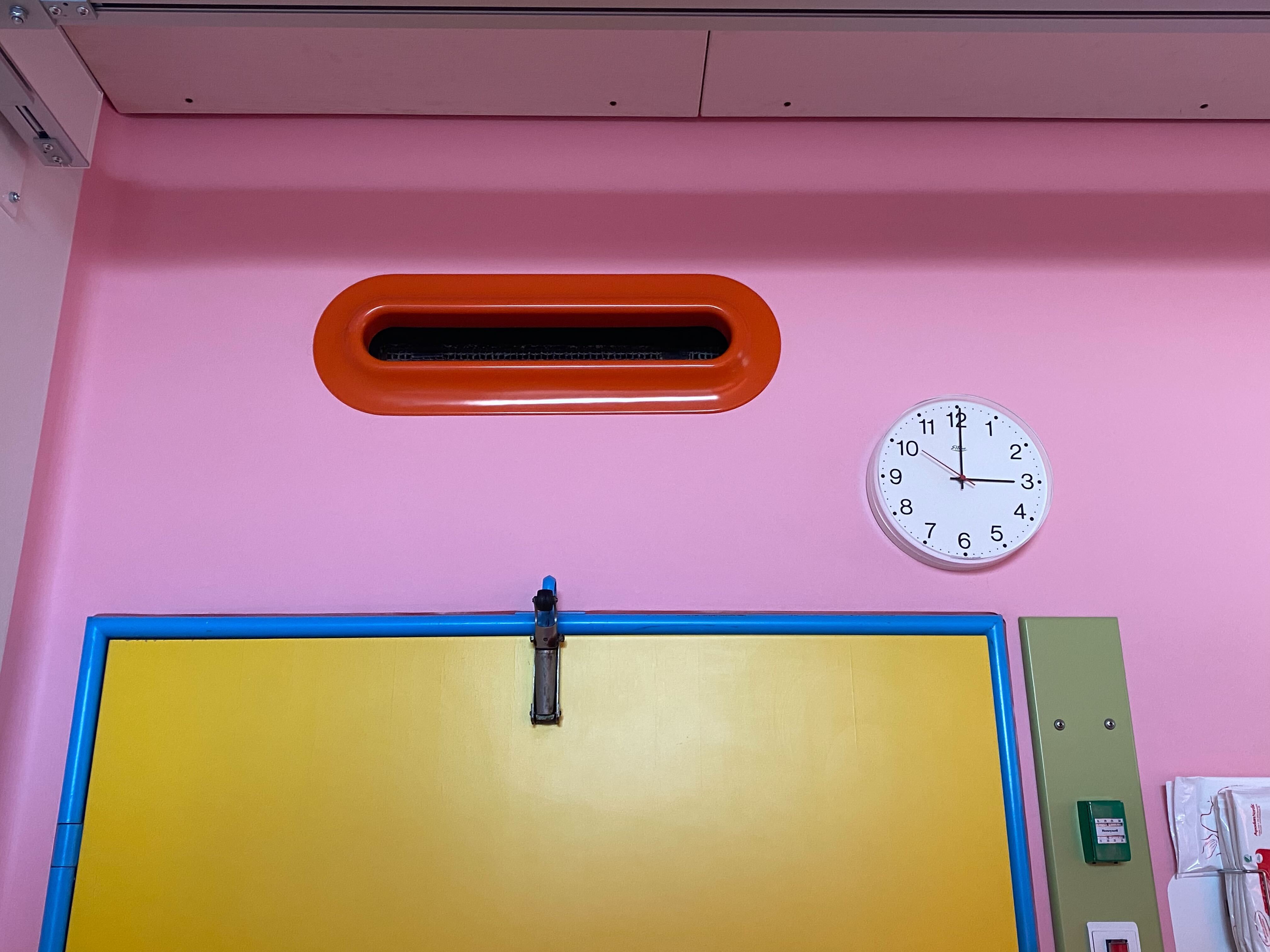 Photo from Herlev Hospital showing a yellow door from a patient room. The wall is painted pink and the door frame is blue. Color design by Paul Gernes.