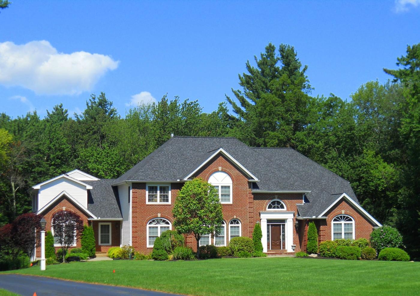 Brick colonial home with a completed dark architectural shingle roof