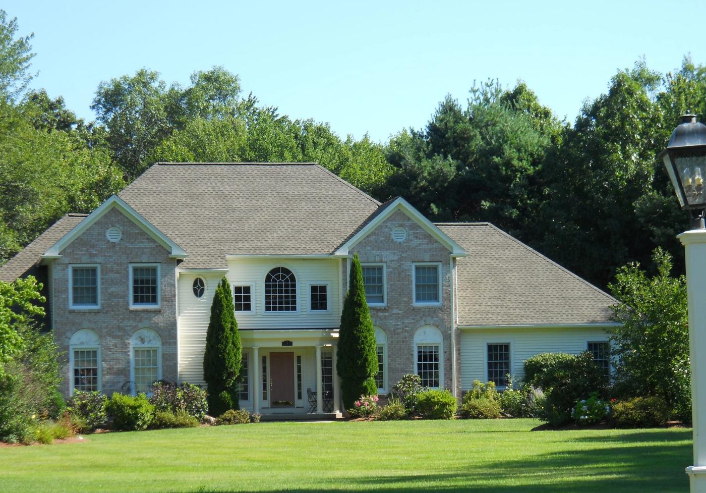 Brick colonial home with a completed hip roof in architectural shingle