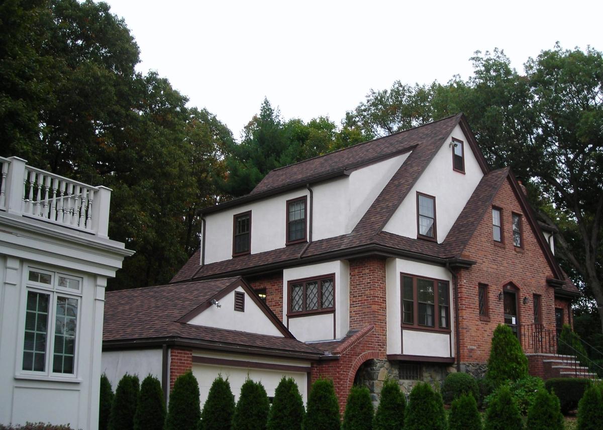 Brick and stucco Tudor home with a newly completed brown shingle roof
