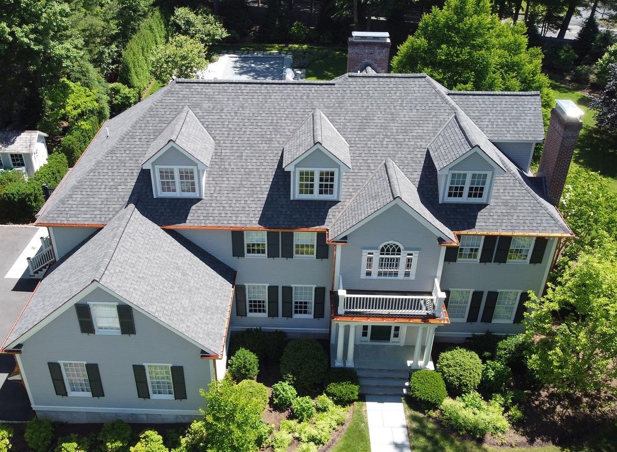 Aerial view of a completed gray architectural shingle roof with copper gutters on a Greater Boston colonial