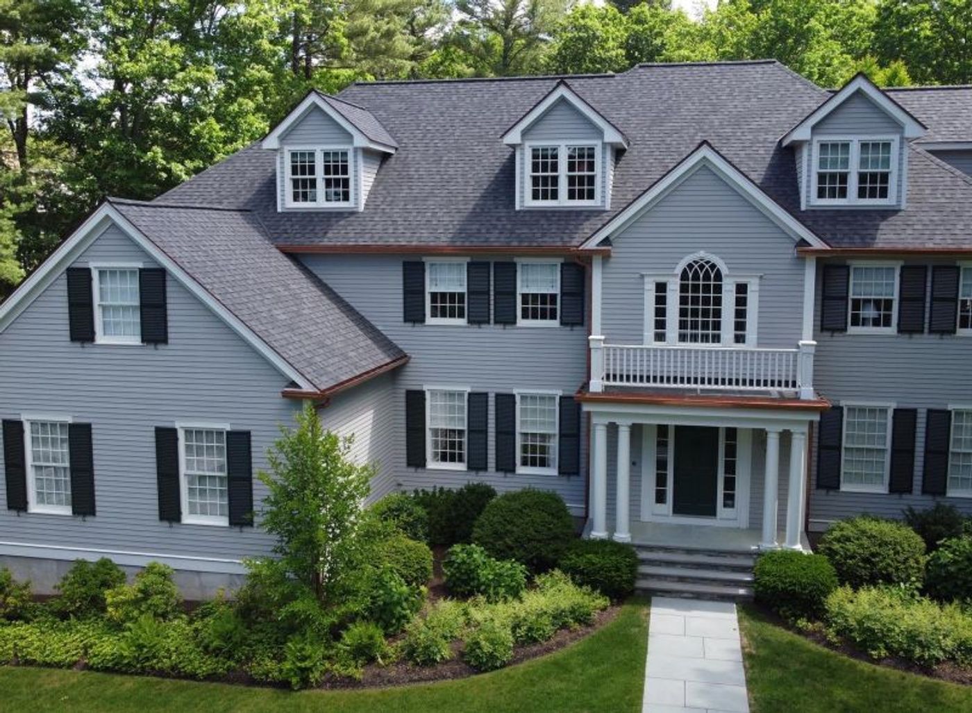 Aerial view of a gray clapboard colonial with a new shingle roof, dormers and copper detailing