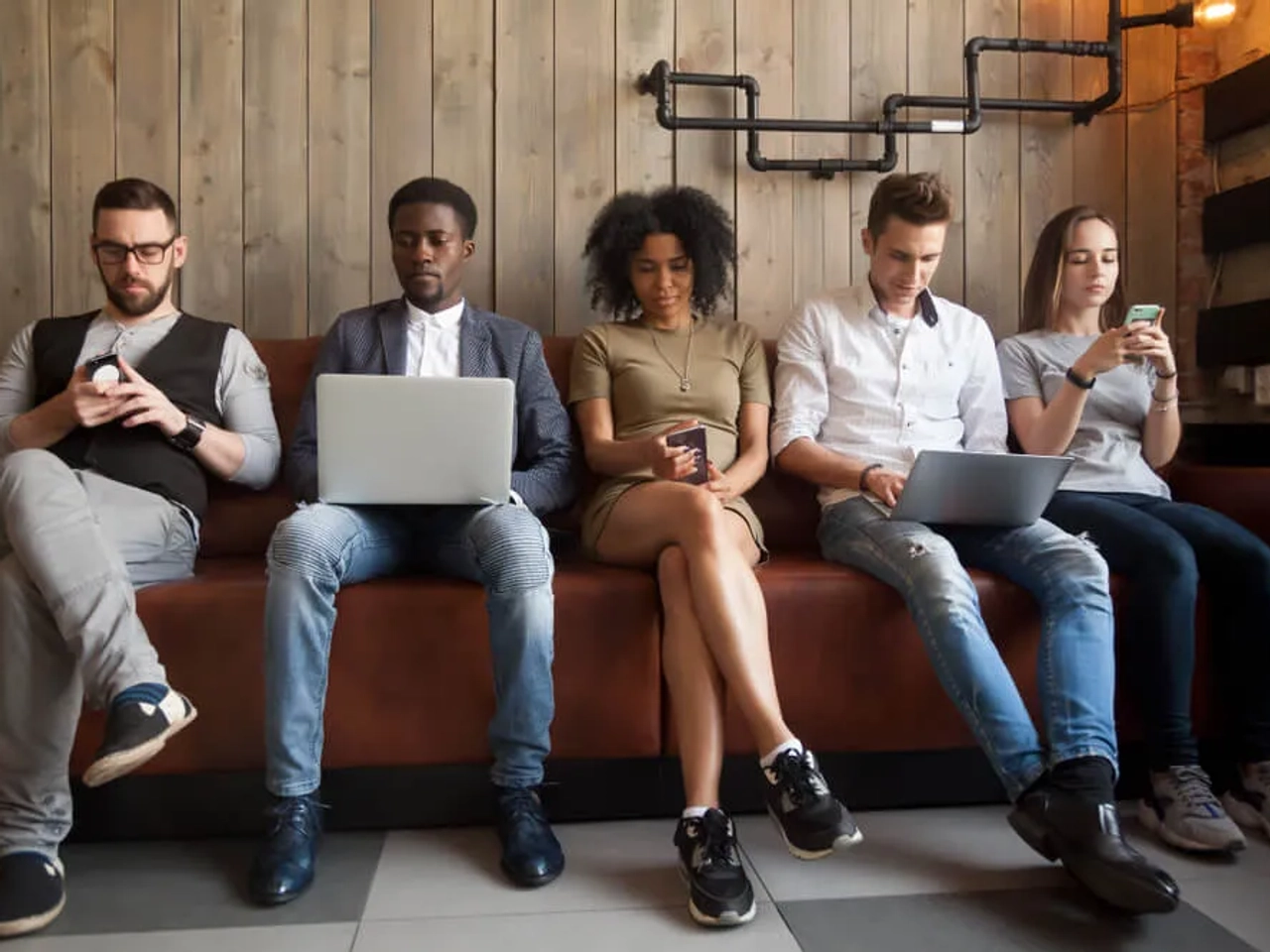 jovens sentados num banco a traballhar nos portateis
