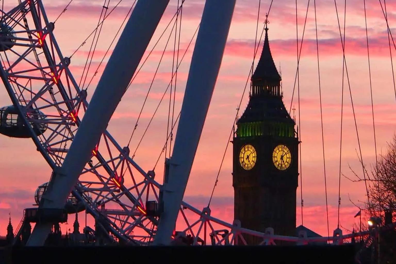 Rueda de Londres y el Big Ben al atardecer, con cielo colorido.