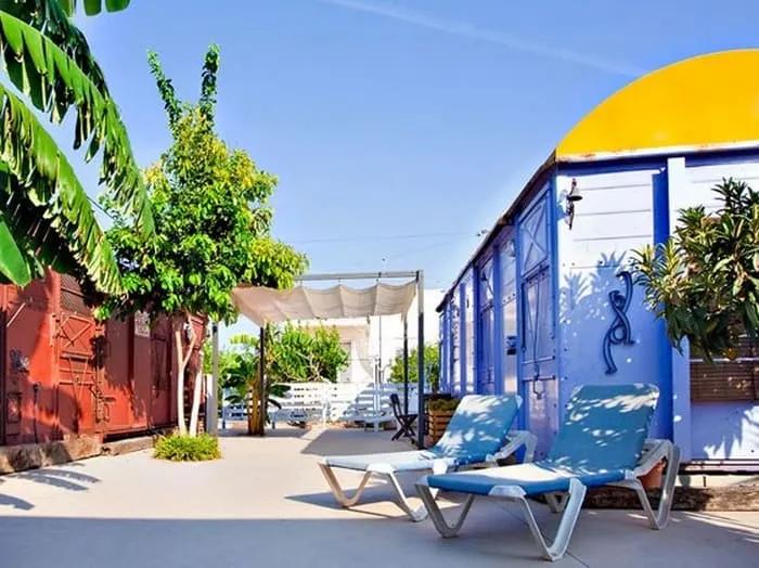 Espacio exterior de un hotel peculiar con sillas, plantas y edificios coloridos.