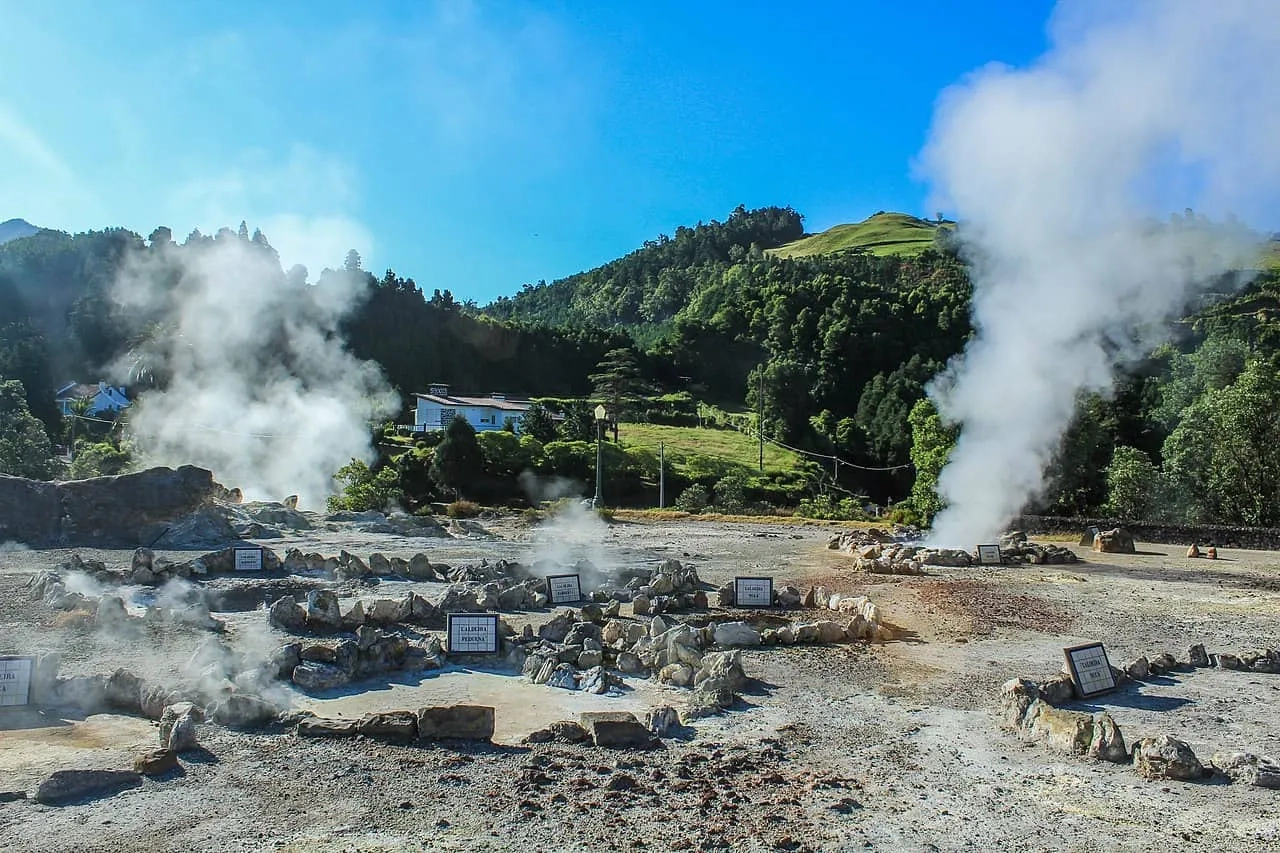 Área geotérmica com fumarolas e vegetação ao fundo em São Miguel, Açores.