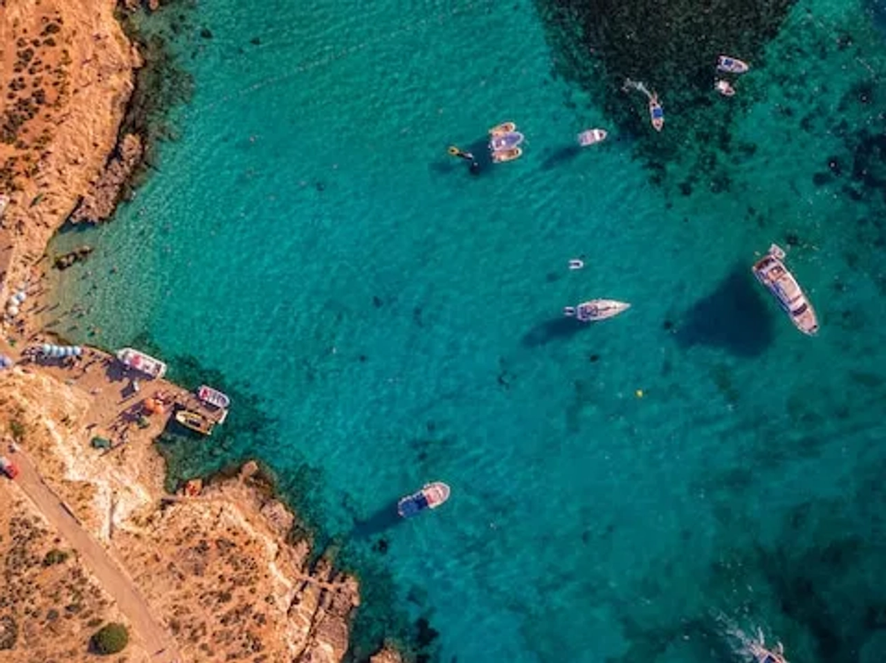 boats in crystal clear water in Comino, Malta