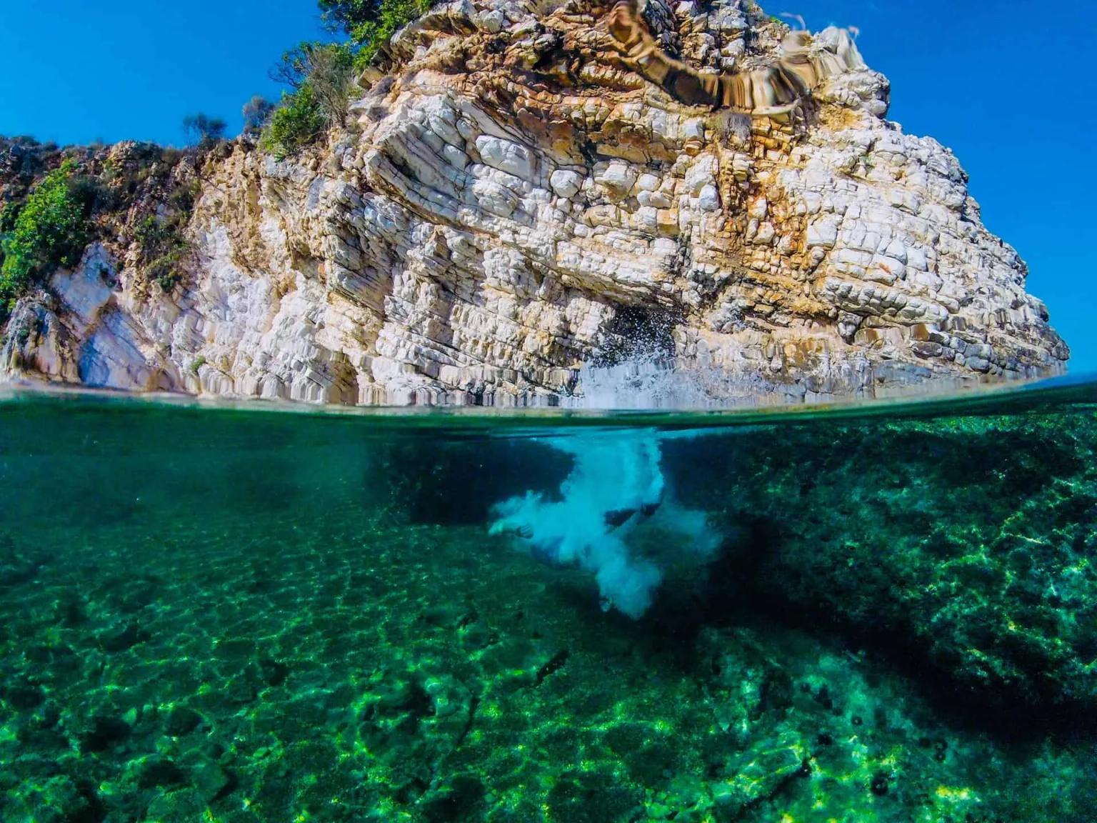 Cenário de praia na Albânia com águas cristalinas e rochas imponentes.