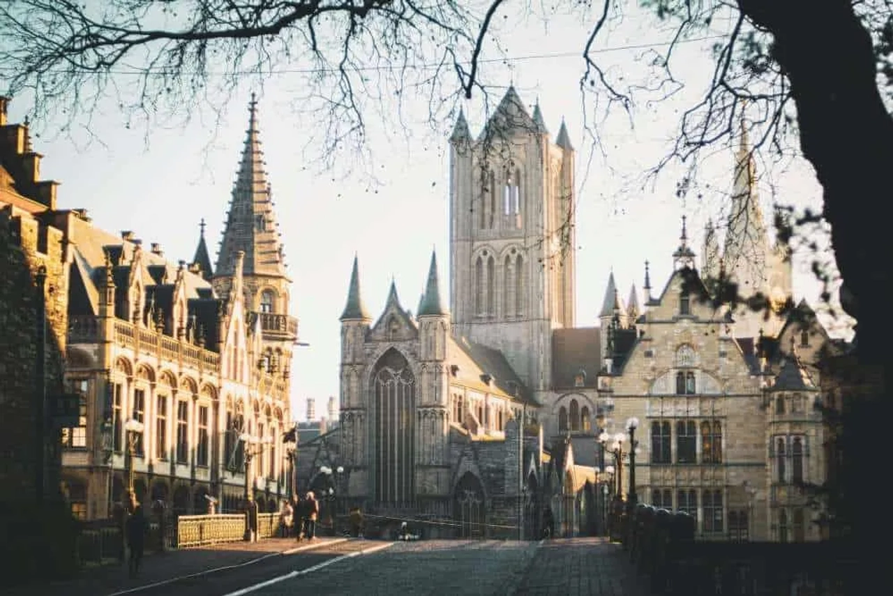 Vista de edificios históricos y una torre en Bélgica al atardecer.
