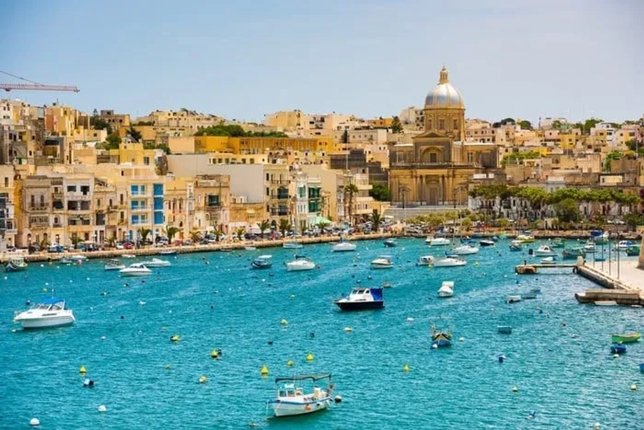 Vista do porto de Malta com barcos e arquitetura histórica ao fundo.