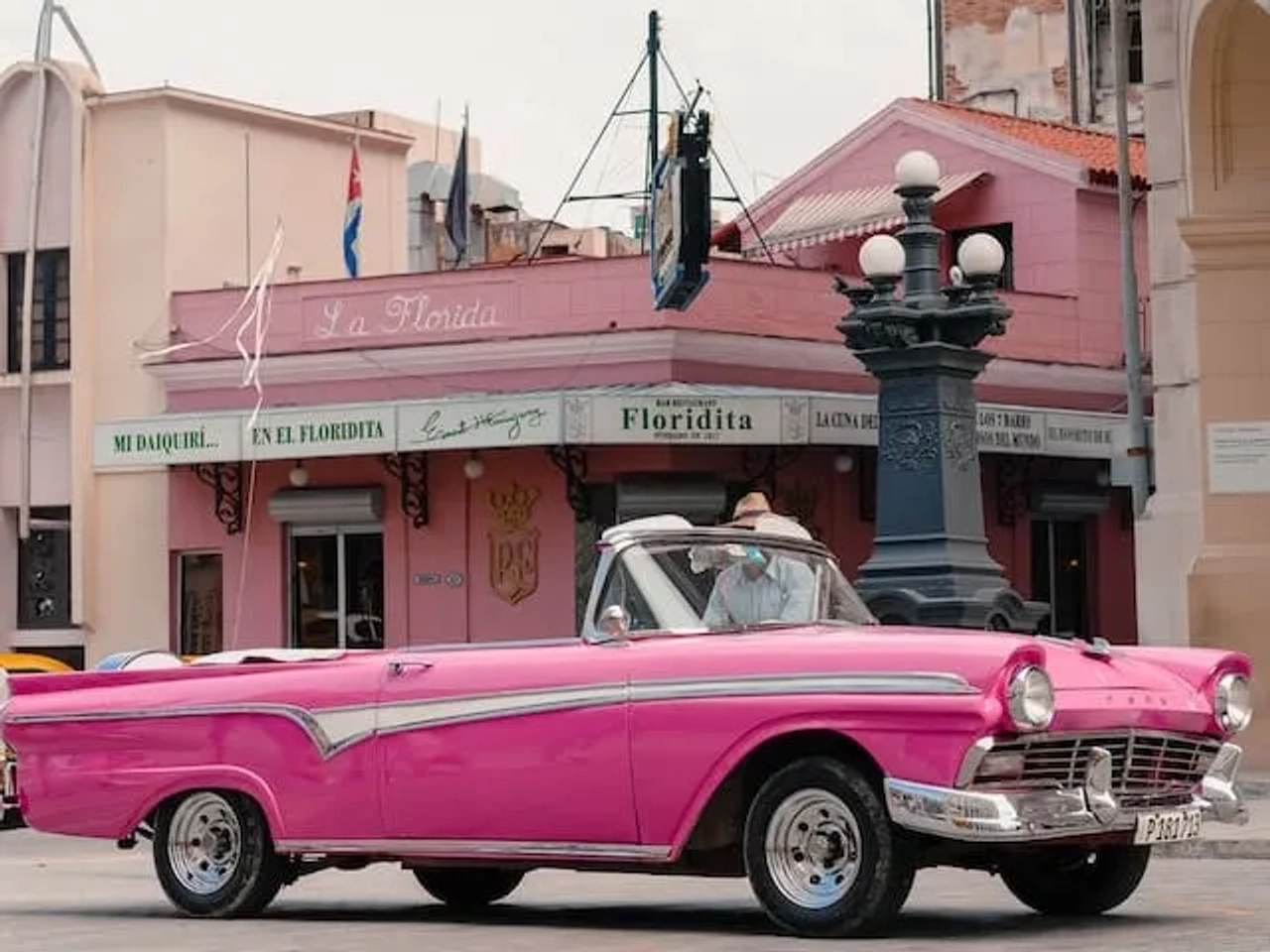 carro cor de rosa a passar em frente ao bar floridita em havana cuba