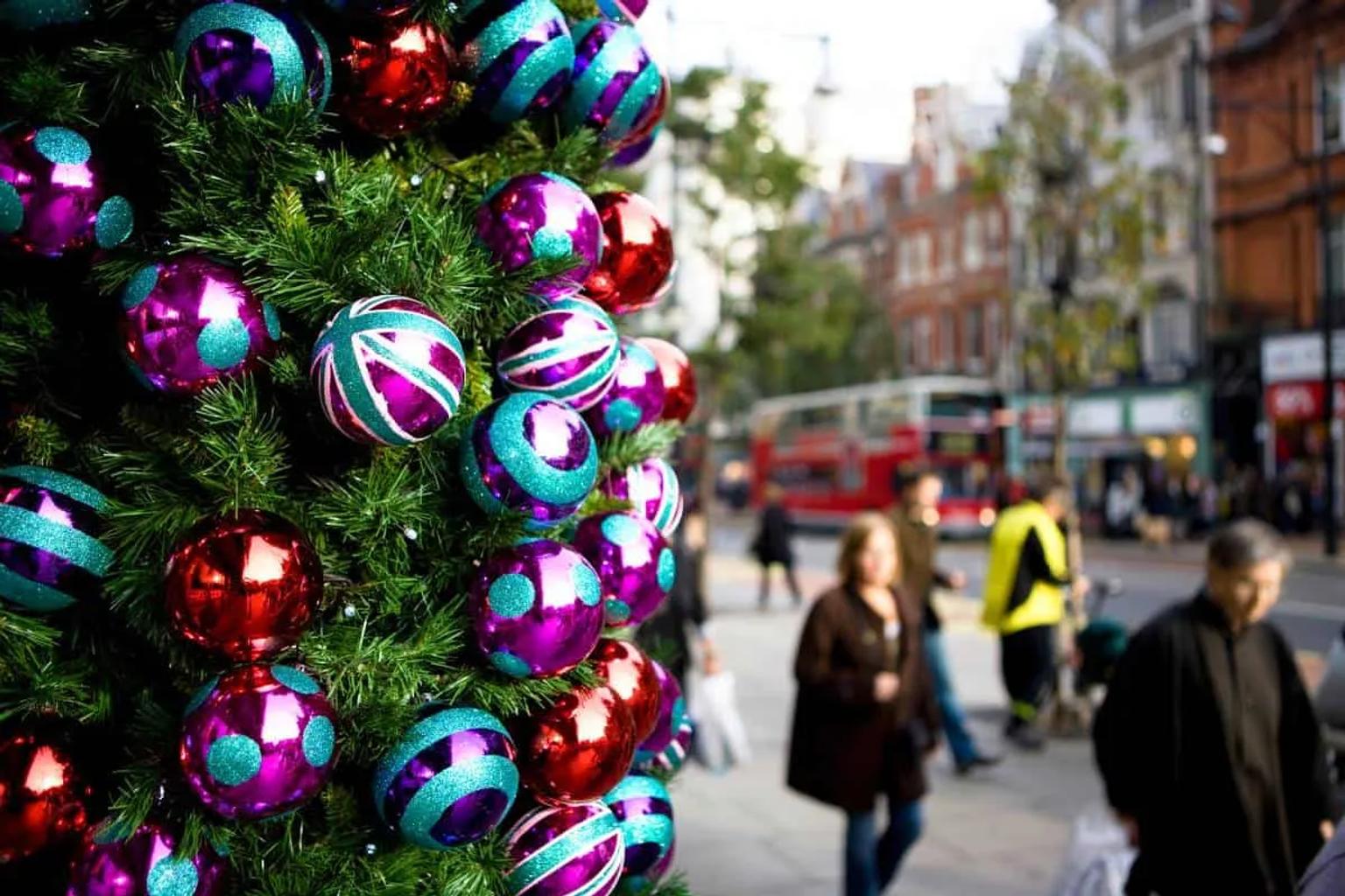 Árbol de Navidad decorado con esferas brillantes en una calle concurrida.