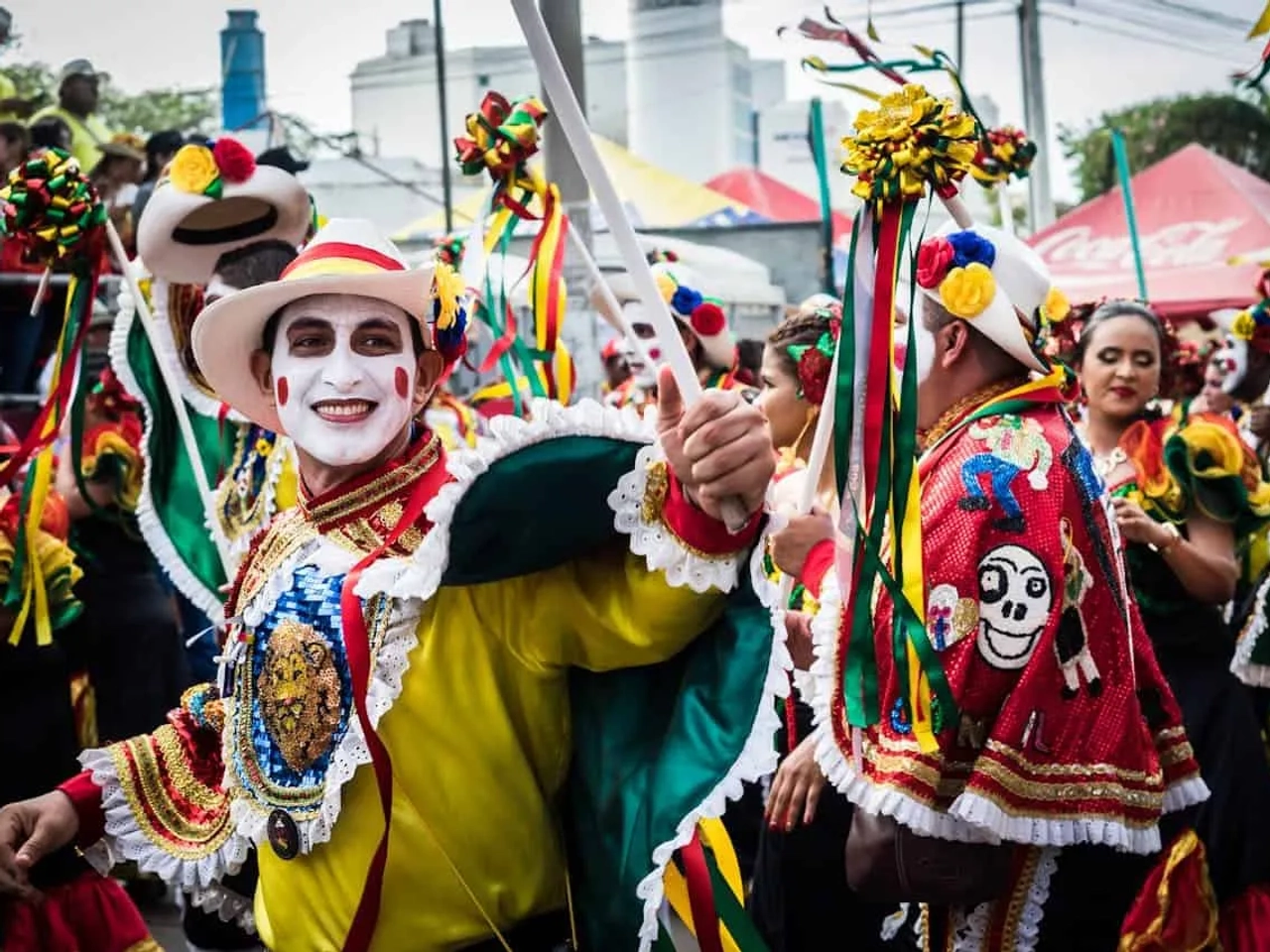 Participantes de carnaval com trajes coloridos e maquiagem festiva em desfile animado.