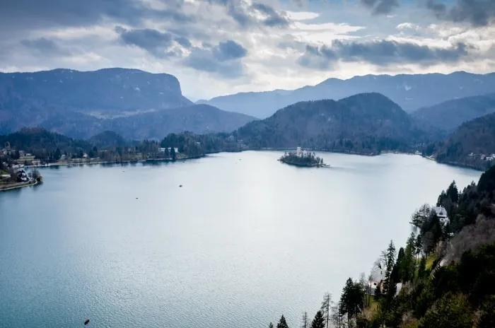 Lago rodeado de montañas y un pequeño islote con un castillo.