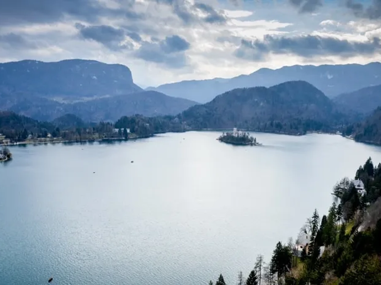 Lago rodeado de montañas y un pequeño islote con un castillo.