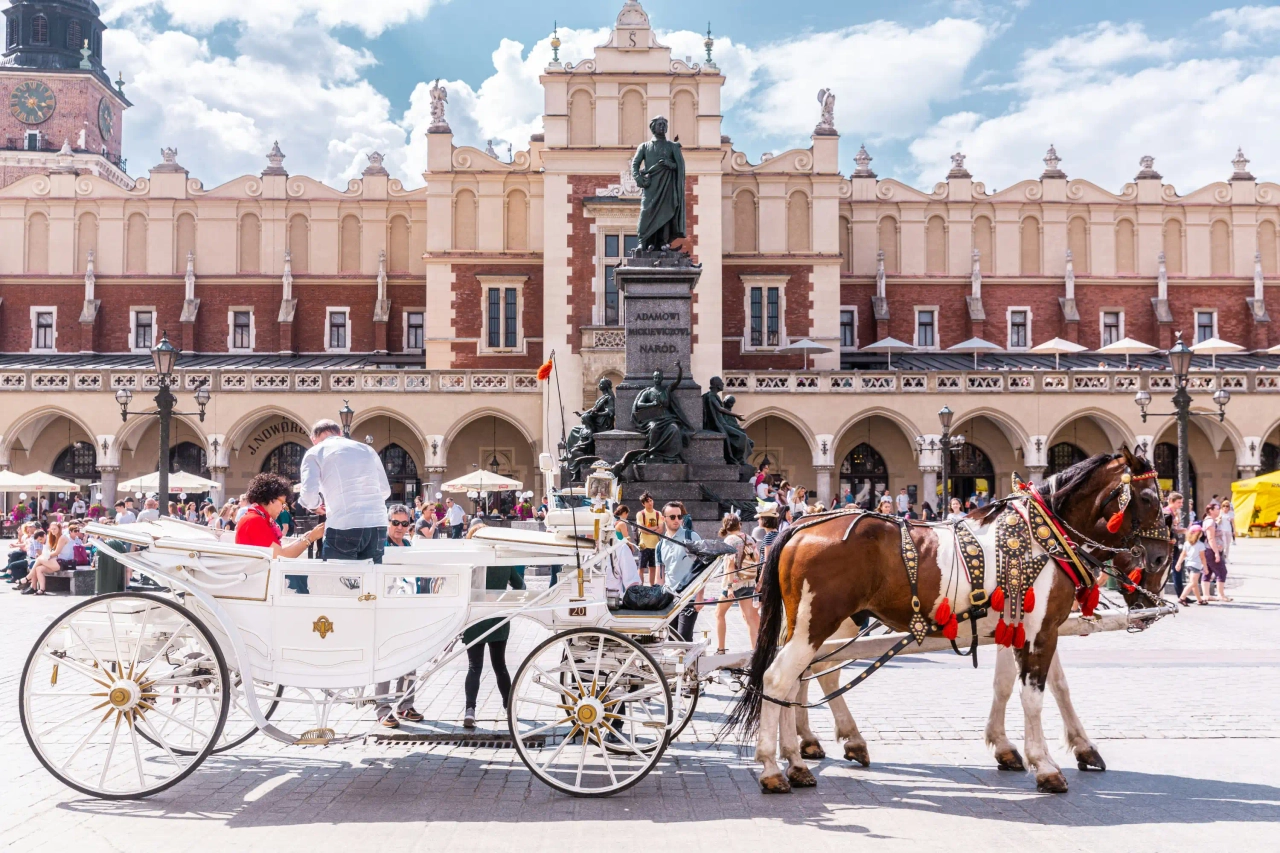 Carruagem puxada por cavalos na praça principal de Cracóvia, junto aos edifícios históricos do centro.