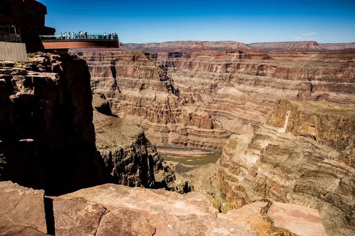 Vista panorámica del Gran Cañón con visitantes en la plataforma de observación.