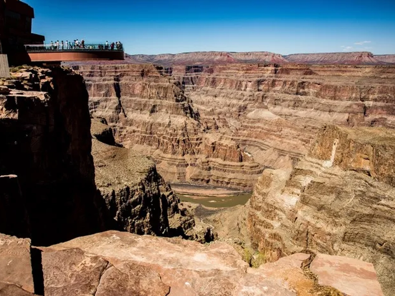 Vista panorámica del Gran Cañón con visitantes en la plataforma de observación.