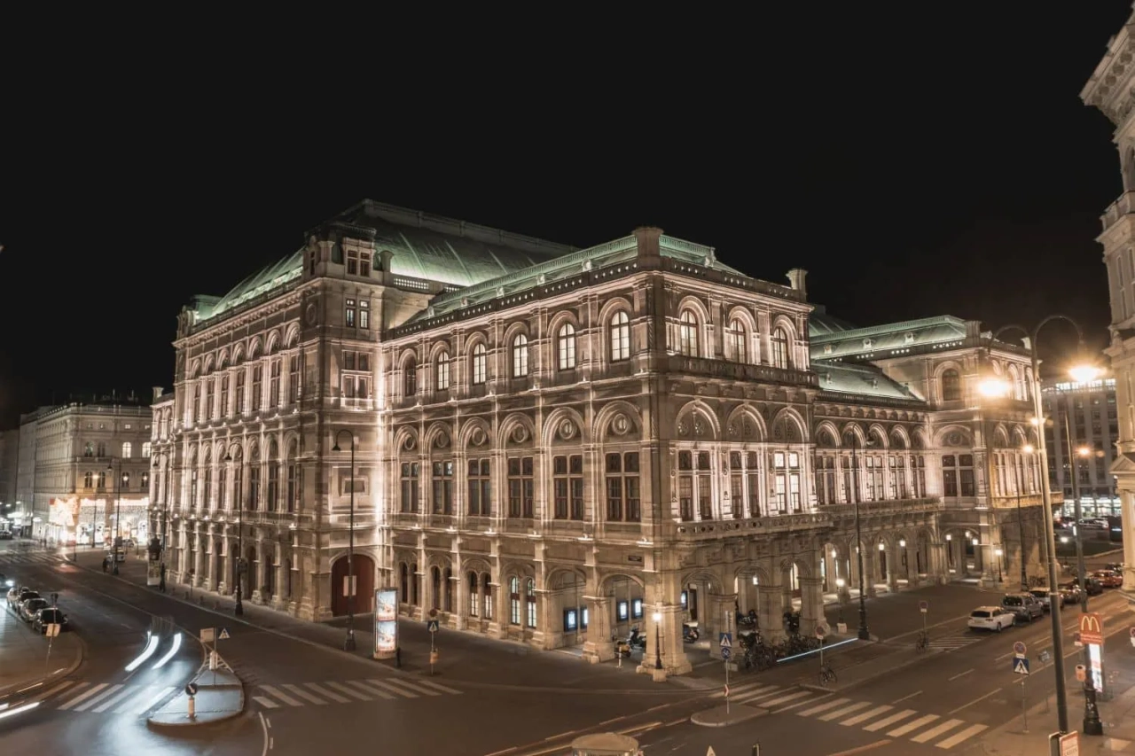 Teatro da Ópera de Viena iluminado à noite, destacando sua arquitetura imponente.