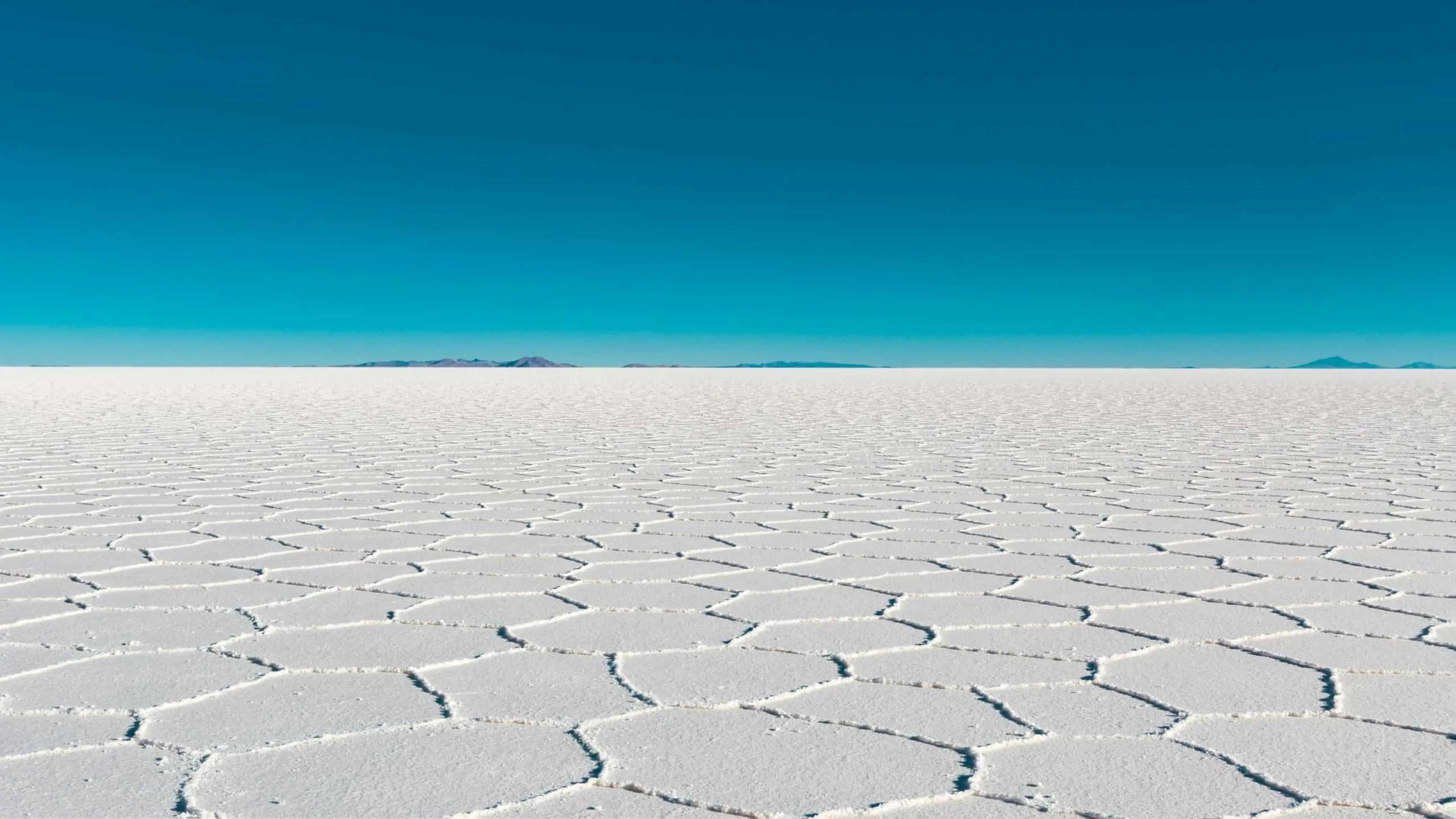 Extensa superficie blanca del Salar de Uyuni bajo un cielo azul despejado.
