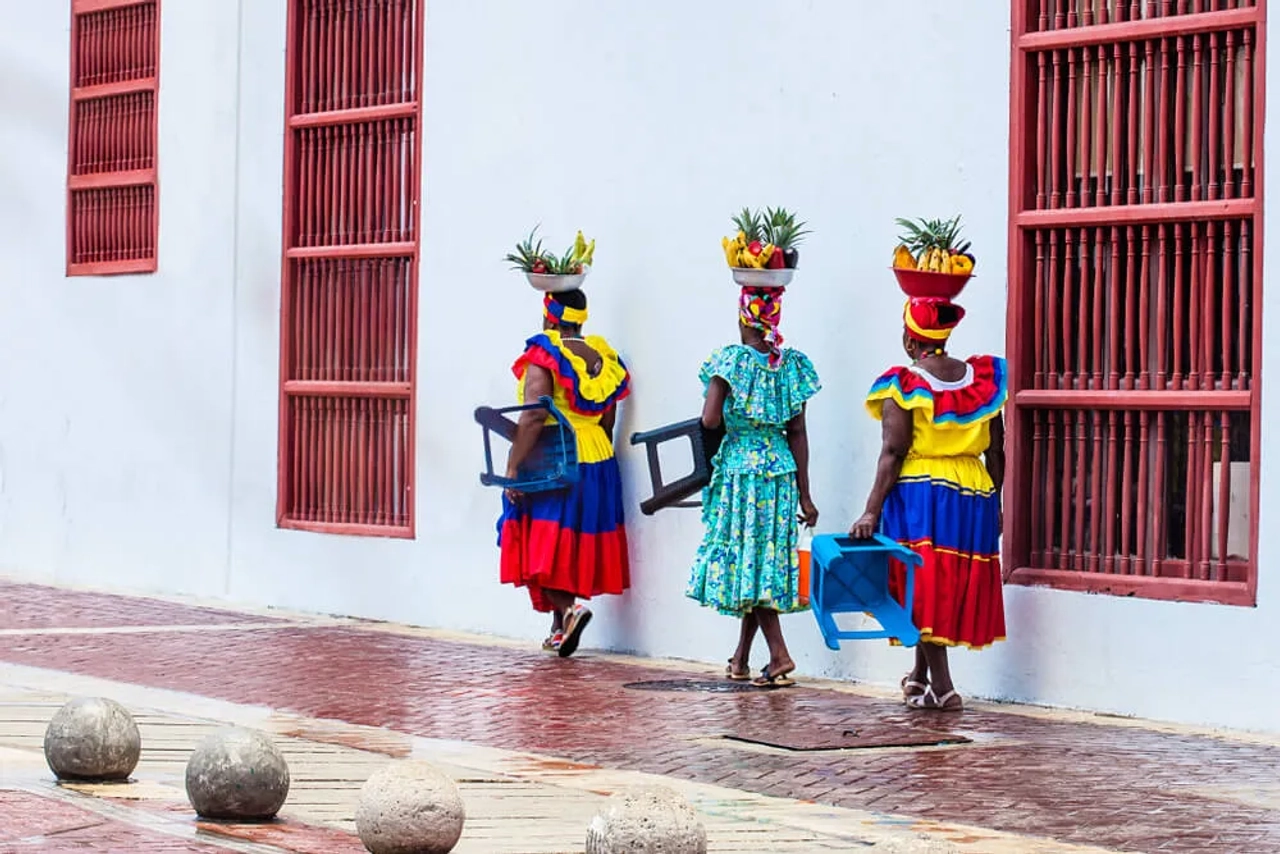 mulheres colombianas com fruta na cabeça e vestidos tradicionais