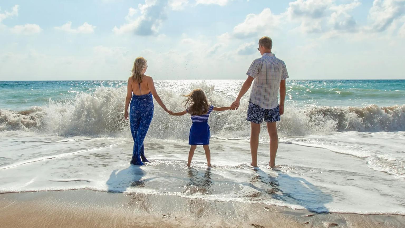 Familia cogida de la mano frente al mar, protegida con un seguro de vida para la hipoteca