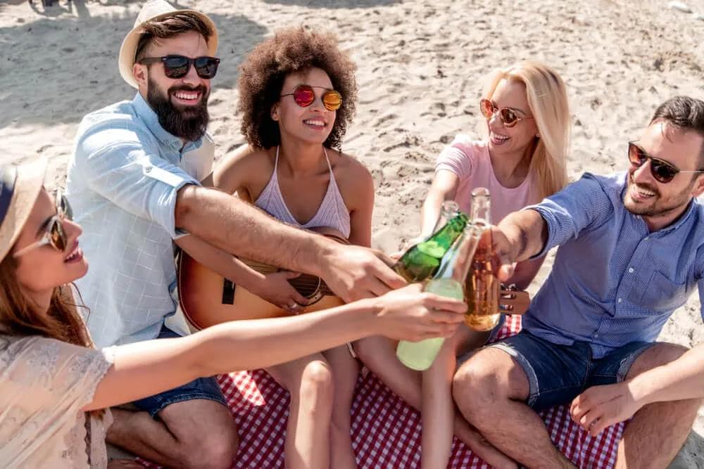 grupo de amigos a beber cerveja na praia