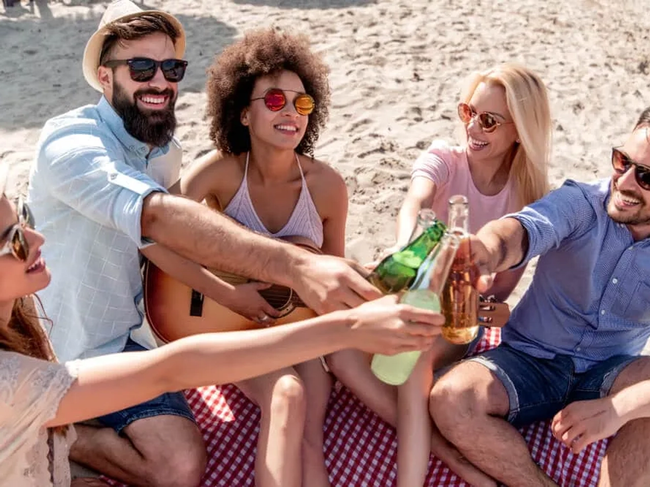 grupo de amigos a beber cerveja na praia