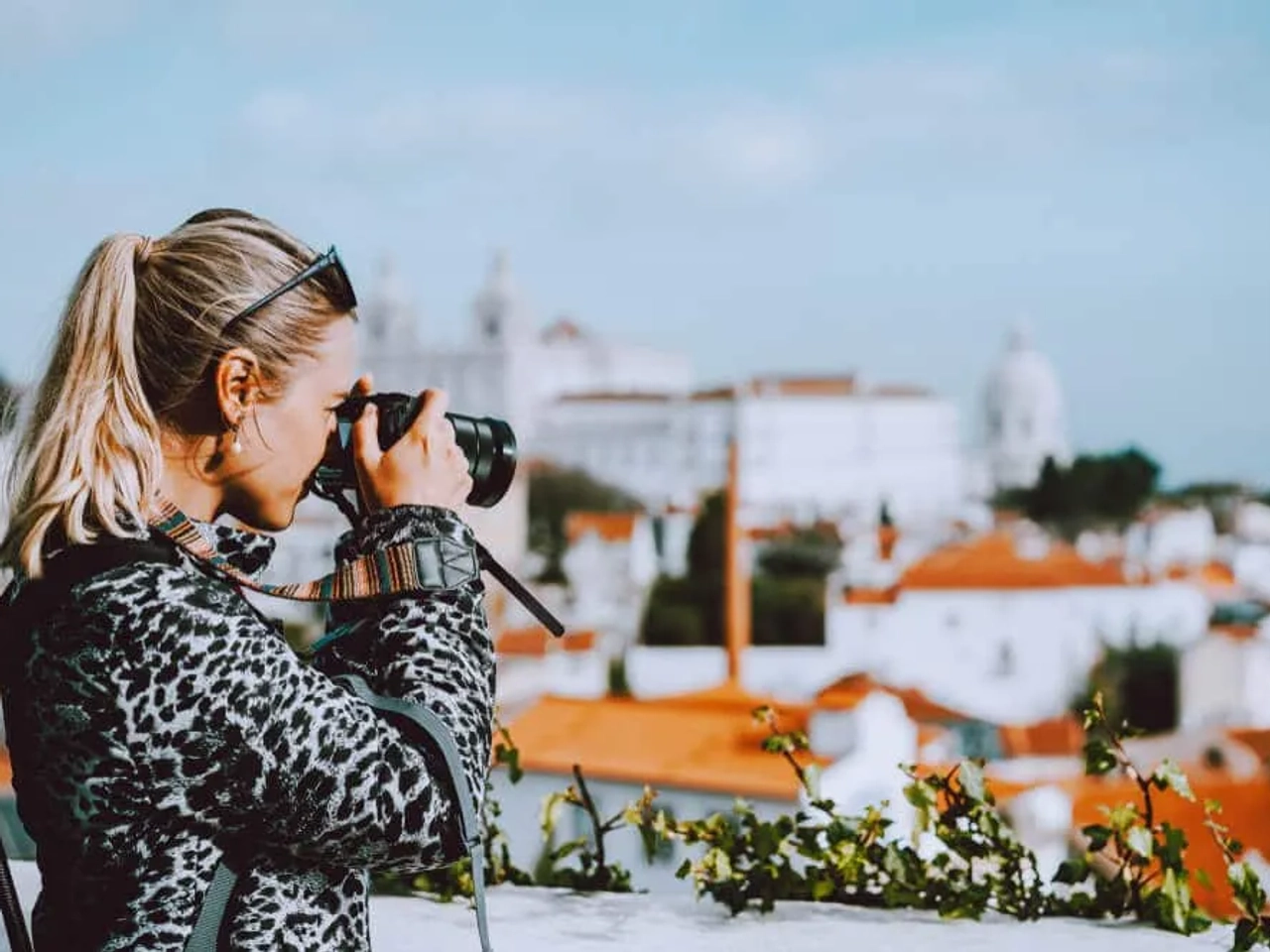 mulher a fotografar lisboa desde o miradouro das portas do sol