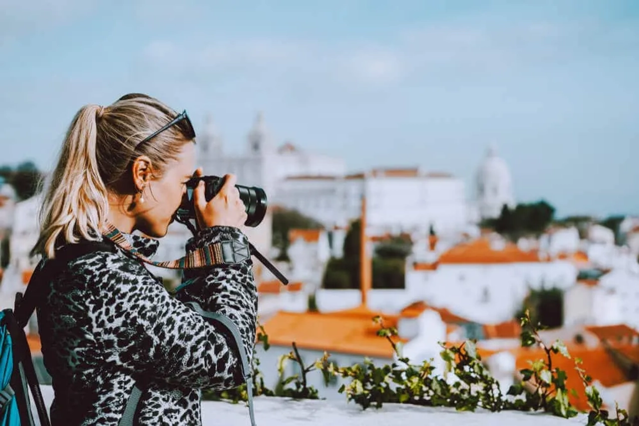mulher a fotografar lisboa desde o miradouro das portas do sol