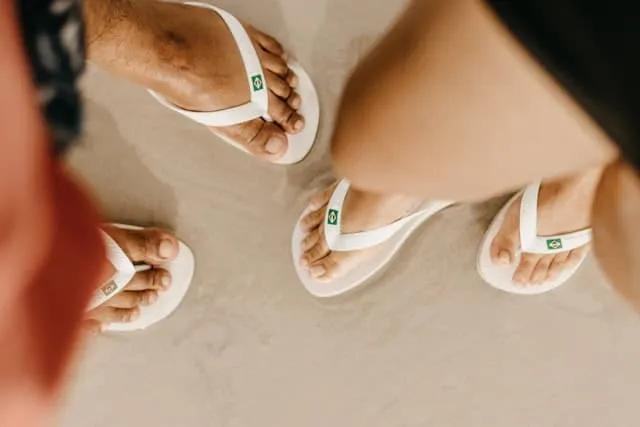 duas pessoas em pé com havaianas brancas