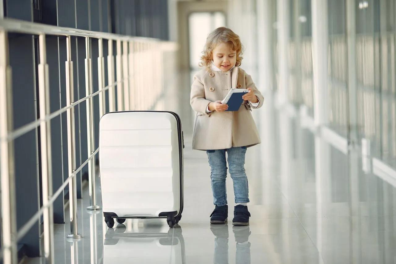 Bambina con passaporto e valigia in aeroporto prima di un viaggio negli Stati Uniti.