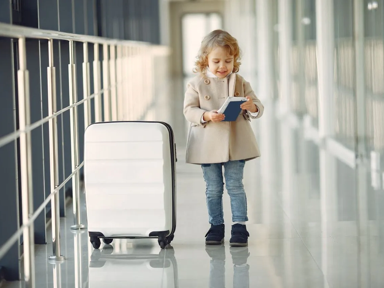 Bambina con passaporto e valigia in aeroporto prima di un viaggio negli Stati Uniti.