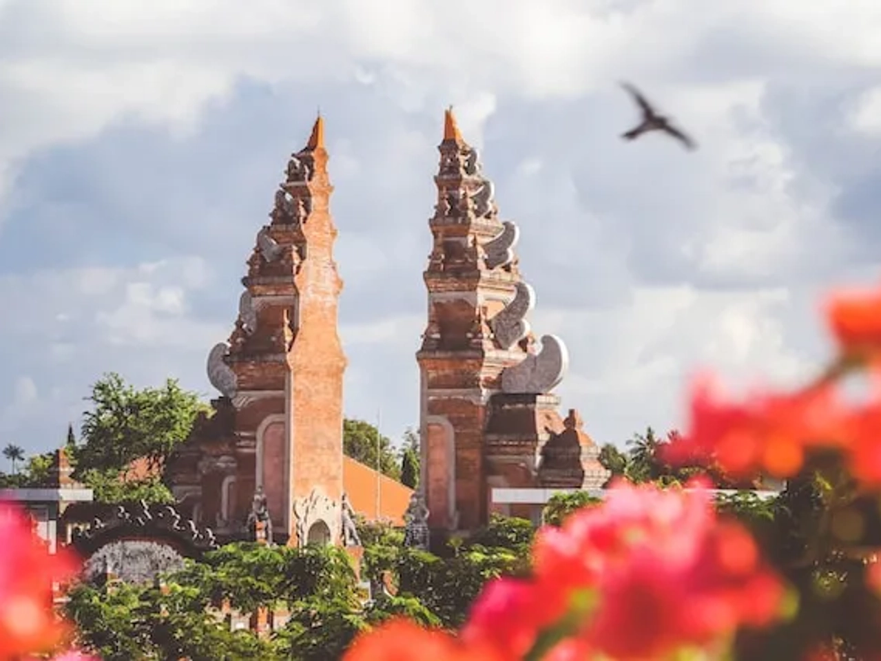 monument with pink flowers and a bird flying over in indonesia
