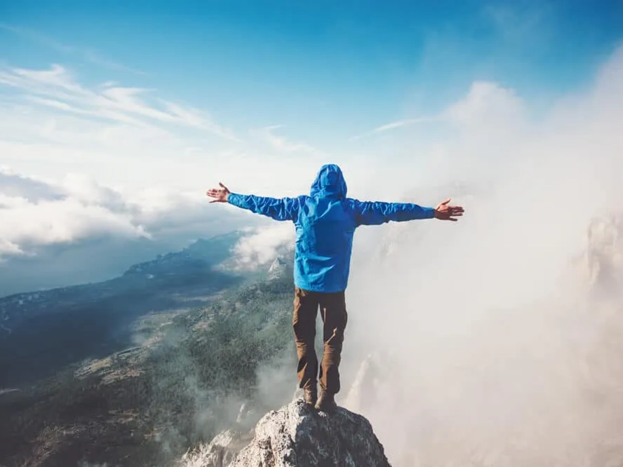 homem sozinho no cume de uma montanha tira foto de braços abertos