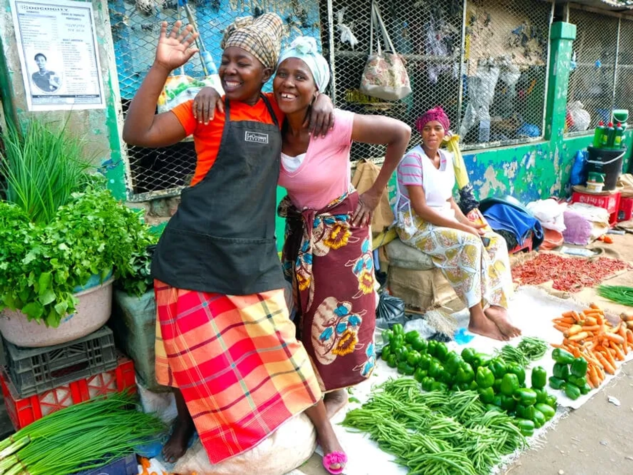 mulheres sorriem num mercado de vegetais em maputo