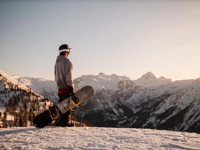 one man holding a snowboard in a mountain
