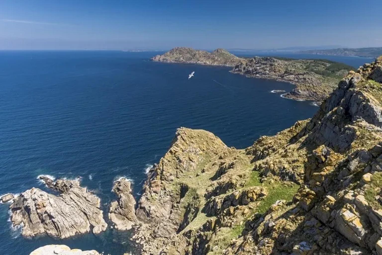 Vista panorâmica das Ilhas Cíes, com mar azul e rochas imponentes.