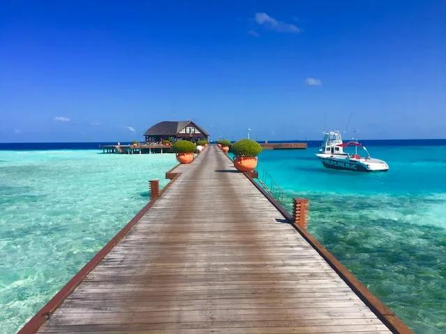 a villa in the maldives with blue water and a boat