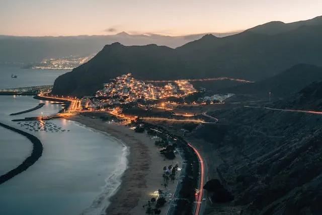por do sol sobre a praia de las teresitas com as casas iluminadas em tenerife - experiência que não podes perder
