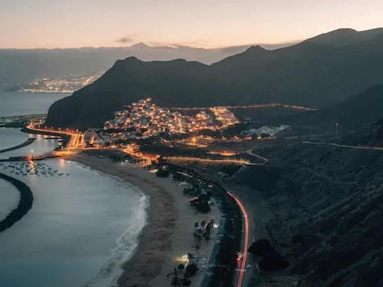 por do sol sobre a praia de las teresitas com as casas iluminadas em tenerife - experiência que não podes perder