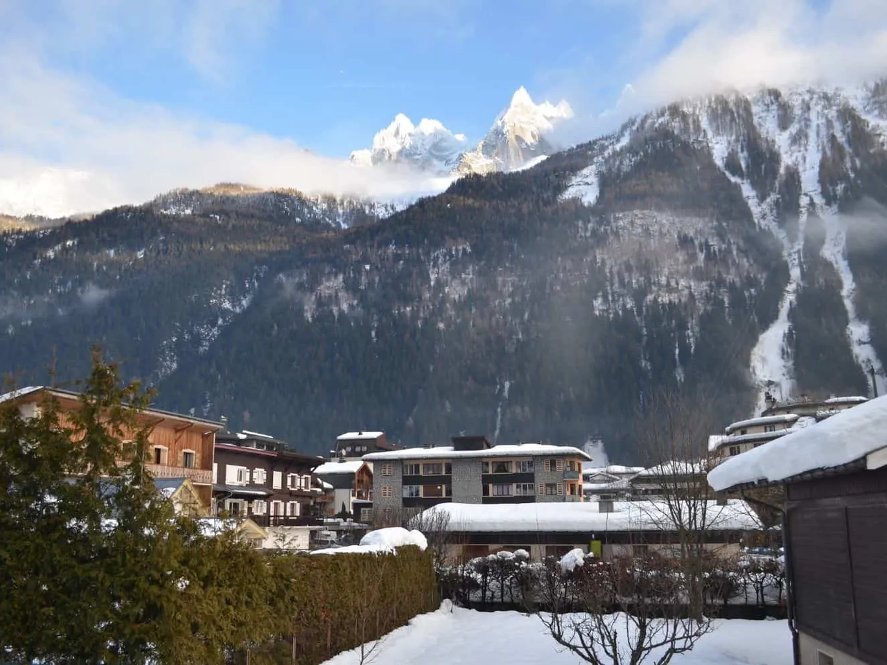 Paisagem montanhosa coberta de neve, com chalés e árvores ao fundo.