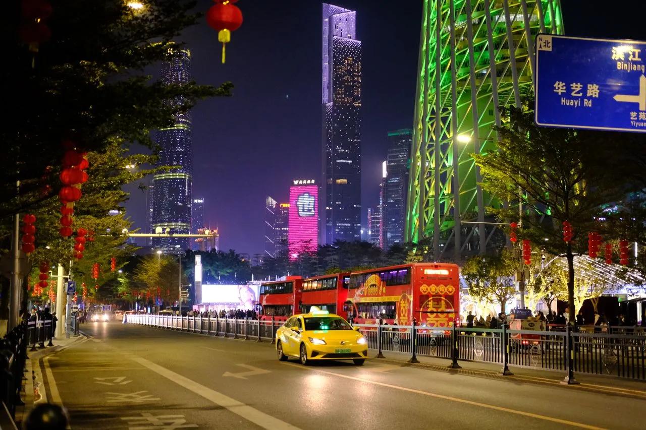 Traffico serale su una strada di Shenzhen con taxi, autobus, grattacieli illuminati e lanterne rosse durante un viaggio in Cina.